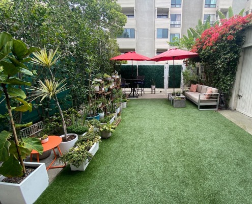 REV Studio's backyard patio Back patio of REV Studio with bright green grass, plants, seating area, and umbrellas